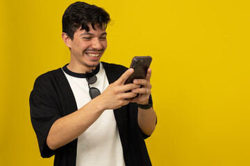Young freckled man with a mustache smiling while chatting on his cell phone on a yellow background...