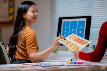 Two female web designers discussing mobile application interface design during meeting at modern...
