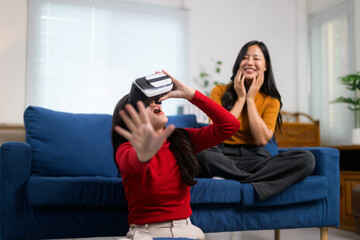 Young woman using virtual reality headset is enjoying videogame with her friend watching her