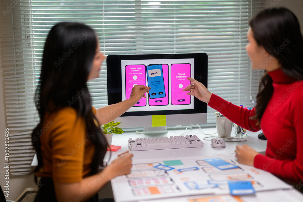 Poster two female ux designers discussing mobile app interface design on computer in the office