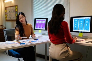 Two female ui/ux web designers working on a new mobile app design project in their office