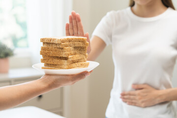 Gluten allergy, asian young woman hand push out, refusing to eat white bread slice on plate in...