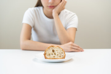Gluten allergy, asian young woman, girl refusing to eat, looking at bread slice on plate in...