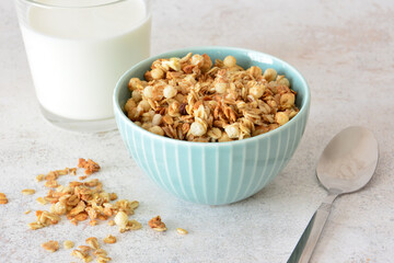 Granola cereal breakfast with milk in a blue bowl with a spoon