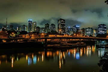 Fototapeta premium Nocturnal Cityscape of Sao Paulo, Brazil: Illuminated Skyline and Iconic Suspension Bridge Over the River