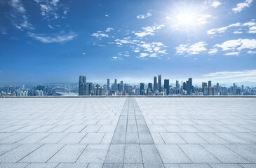 Empty stone square floor with modern city skyline and commercial buildings under a blue sky in...