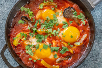 Shakshuka with mushrooms and yellow peppers topped with eggs and cilantro