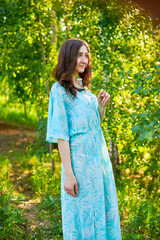 Fototapeta premium A woman in a blue dress stands in a field of green grass against a blue sky.