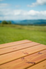 Fototapeta premium Wooden Tabletop with Blurred Green Meadow and Blue Sky Background for Product Display or Mockup
