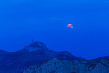 The full red moon rising over the Swiss Alpstein viewed from Schaefler with the summit of Hoherkasten at the background