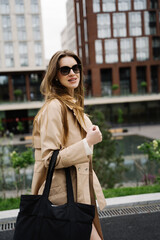 Fototapeta premium Young pretty beautiful woman in trench coat and sunglasses