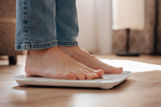 Young woman stands on scales symbolizing weight loss journey