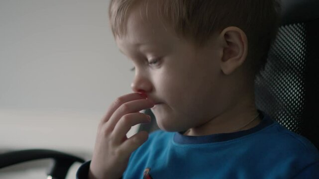 child picks his nose. a little boy stuck his finger up his nose