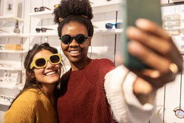 Smiling friends taking a selfie in a sunglasses store
