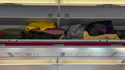 Tangled tangibles in overhead bins, a symphony of travel chaos, whispering tales of wanderlust on...