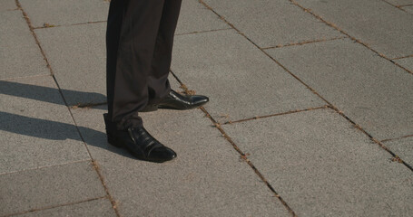 Close-up of businessman wearing suit and shoes standing on asphalt, breathing fresh air, break time