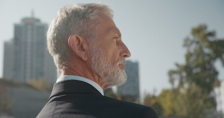 Mature man looking at office building with interest, dreaming of building a company, future vision