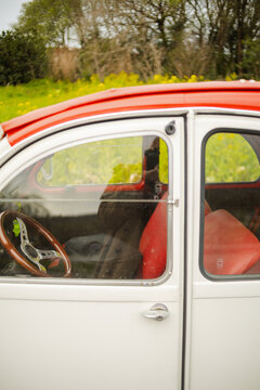 Classic Citroen car with red interior in nature with yellow flowers