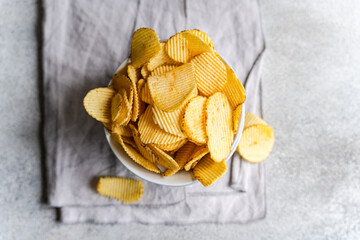 Homemade potato chips in a bowl on a gray background
