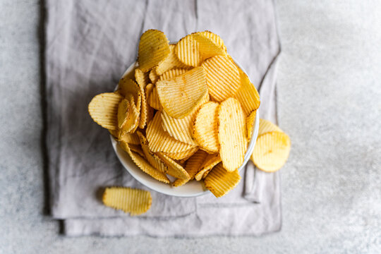 Homemade potato chips in a bowl on a gray background