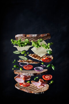 Floating layered sandwich ingredients against dark background