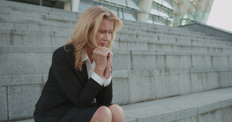 Upset woman in business suit sitting alone on stairs, failure at work, business problems