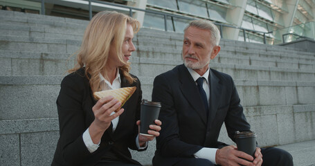 Company employees having lunch outdoors, eating fast food at workplace