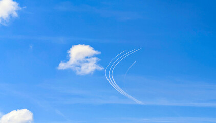 Aerobatic jet trails curving in clear blue sky