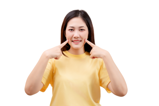 Asian young beautiful smiling in a yellow shirt and pointing to her cheeks with both index fingers.