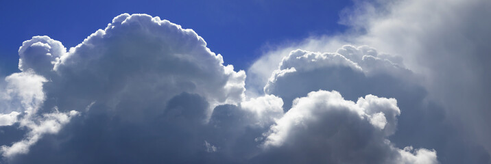 Majestic cumulus clouds drifting across a vibrant blue sky, hinting at an approaching storm during the afternoon
