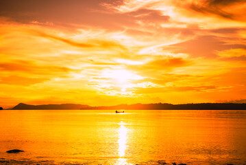 Obraz premium Sunset on the beach with the silhouette of mountains and fishermen with their boats at sea