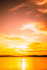 Sunset on the beach with the silhouette of mountains and fishermen with their boats at sea
