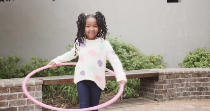 Girl spinning hula hoop outdoors, having fun during active playtime
