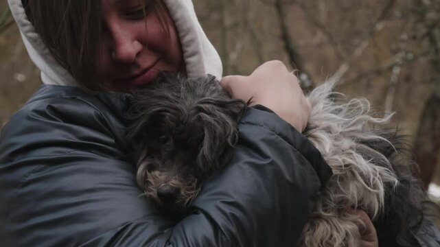 A compassionate woman hugs an abandoned shaggy dog, giving it warmth, safety and hope, symbolizing animal rescue and unconditional love. The woman saves the dog by holding it tenderly in her arms.