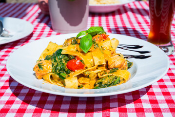 delicious pasta with salmon and vegetables in an Italian restaurant on the summer terrace