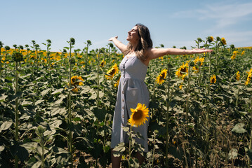 Happy woman arms raised and enjoying in sunflower field.