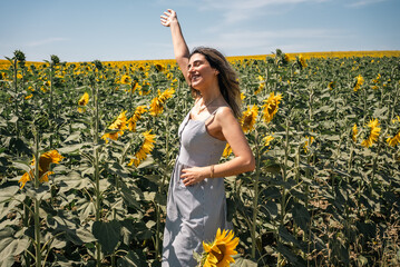 Happy woman arms raised and enjoying in sunflower field.