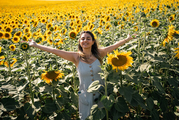 Happy woman arms raised and enjoying in sunflower field.