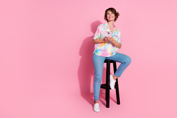 Full size photo of pretty young lady sit stool look empty space wear shirt isolated on pink color...