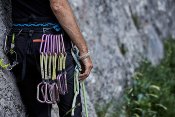 Climber prepares for ascent with gear attached in a natural setting at a rock face