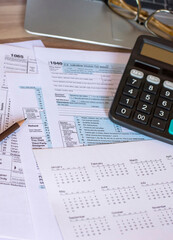 Planning, Budget, and Tax Concept. Individual Income 1040 Tax Form and calculator for individual income. According to United States, season to pay and deadline for tax payment-vertical concept.