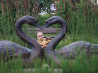 preschool boy with glasses squatting in park among lavender flowers, view through frame, framing,...