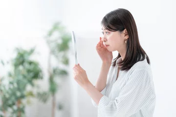 Fotobehang 手鏡を見て悩む女性 © naka