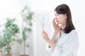 Fotobehang 手鏡を見て悩む女性 © naka