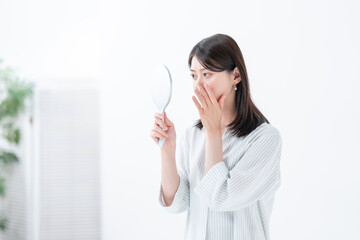 手鏡を見て悩む女性