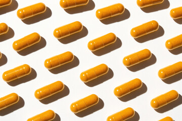 Minimalist pattern of bright yellow curcumin capsules on a white background, representing modern wellness supplements and functional health trends
