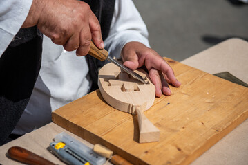 Woodcarvers hands carving decorative patterns on wood with traditional tools
