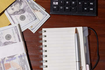 A minimal desk setup showing cash placed beside a notepad and calculator, representing financial...