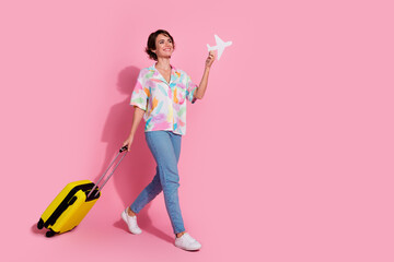 Full size photo of lovely young woman suitcase walk empty space wear shirt isolated on pink color...