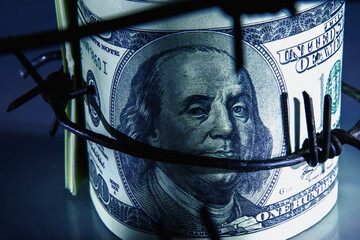 Economic warfare, sanctions and embargo busting concept. Top view of US Dollar bills money wrapped...